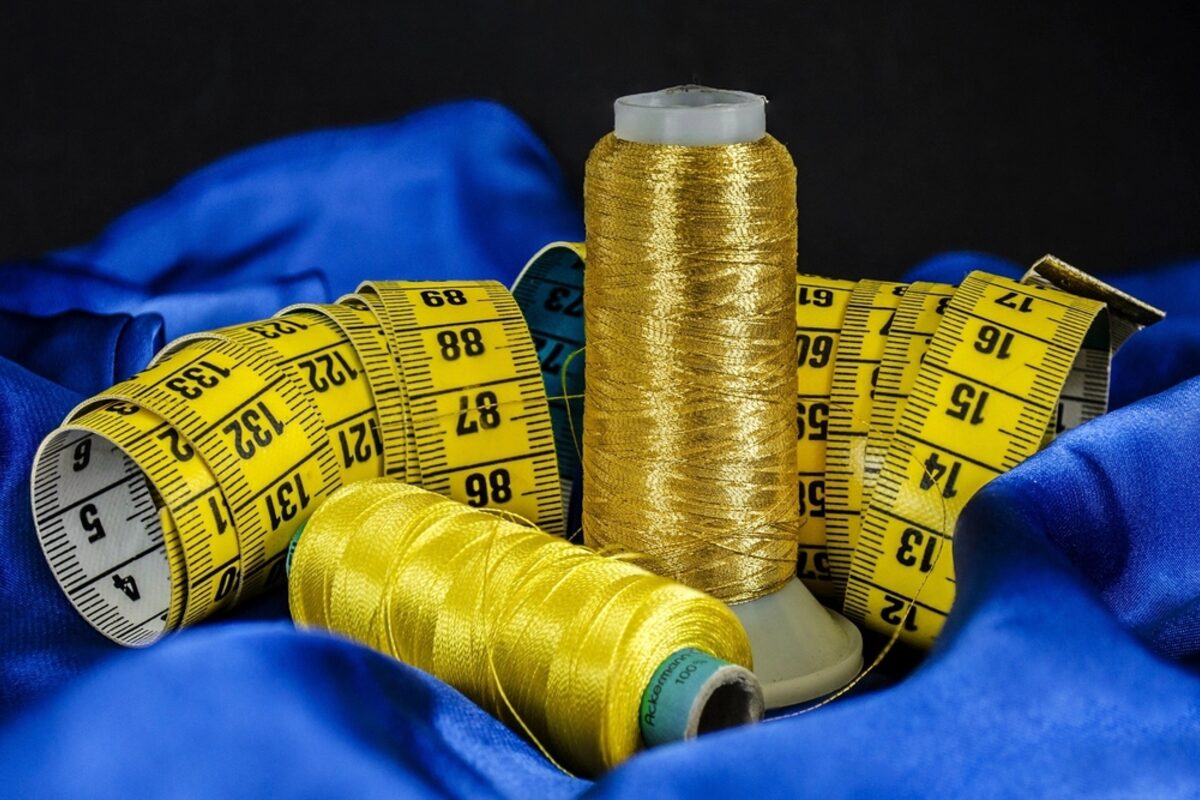 Fita métrica e linha dourada sobre tecido, itens do kit básico do aluno de corte e costura