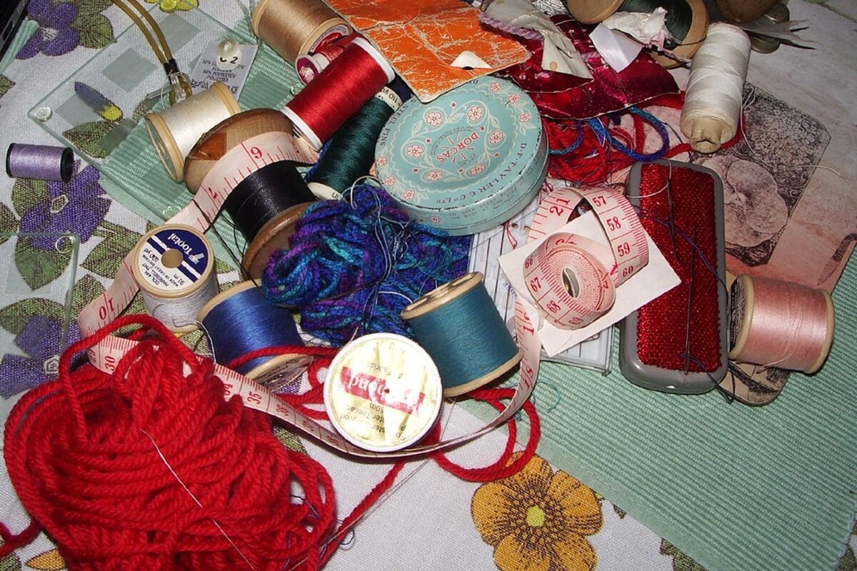 Mesa de trabalho de costura com linhas, tecidos e ferramentas — a sala de aula do autodidata
